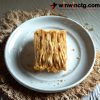 A rectangular block of Traditional Loitta Dried Fish sits on a white plate, surrounded by a textured beige mat.
