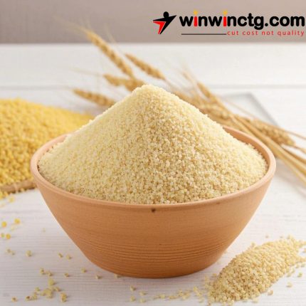 A brown bowl filled with finely ground couscous, with spilled grains nearby and wheat stalks in the background.